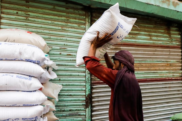 A labourer stacks sacks of sugar outside a shop at a wholesale market in Karachi, Pakistan June 9, 2023. REUTERS/Akhtar Soomro/File Photo