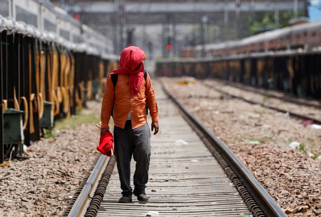 A man covers his face using a cloth to shield himself from the sun as he inspects railway tracks during a hot summer day in New Delhi, India, June 18, 2024. REUTERS/Priyanshu Singh/File Photo