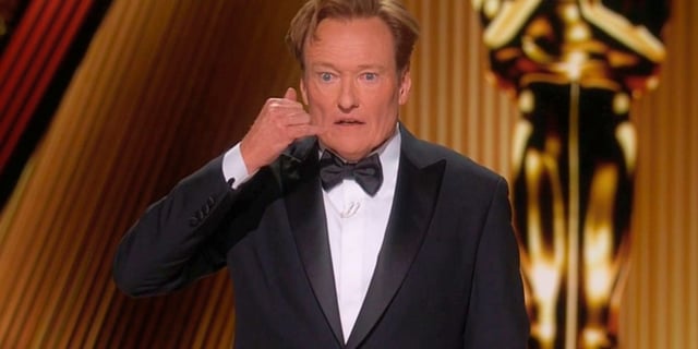 Conan O'Brien makes a "phone gesture" at the 97s Academy Awards.