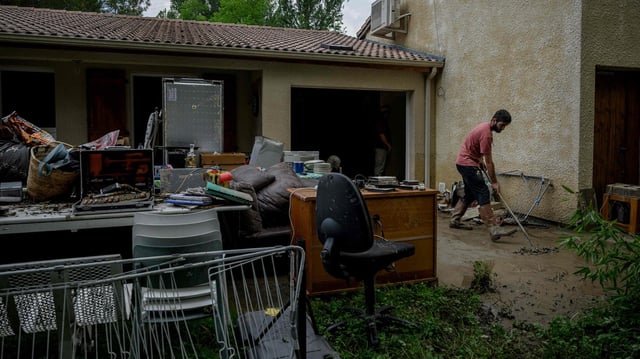 Ein Mann kehrt von Unwetter verursachten Schlamm vor einem Haus in der Ortschaft L'Honor-de-Cos, Frankreich.
