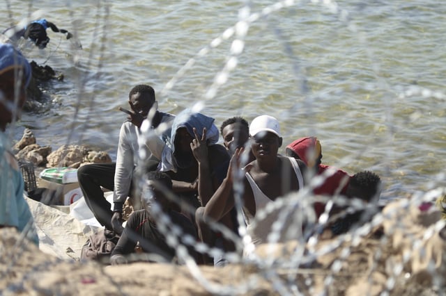 FILE - Migrants gather in an area near the Libyan-Tunisia border, as Libyan security forces and Libyan Red Cross workers distribute food aid to them on Sunday, July 23, 2023. (AP Photo/Yousef Murad, file)