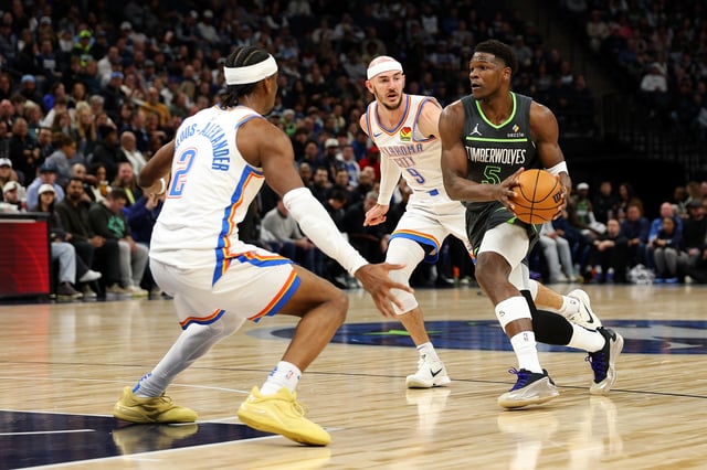 Anthony Edwards #5 of the Minnesota Timberwolves drives to the basket against Alex Caruso #9 and Shai Gilgeous-Alexander #2 of the Oklahoma City Thunder in the first quarter at Target Center on February 23, 2025 in Minneapolis, Minnesota.