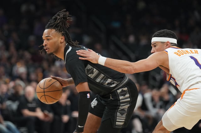 Apr 11, 2025; Phoenix, Arizona, USA; San Antonio Spurs guard Stephon Castle (5) dribbles against Phoenix Suns guard Devin Booker (1) during the first half at Footprint Center. Mandatory Credit: Joe Camporeale-Imagn Images