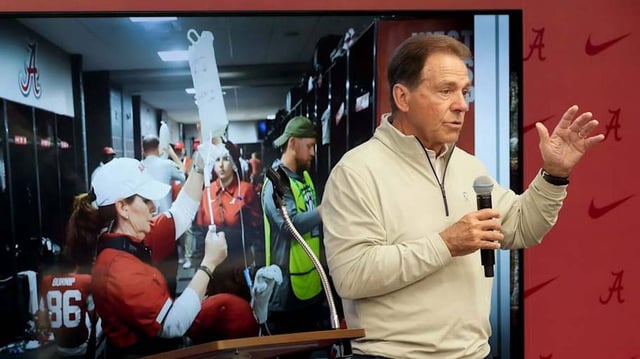 Feb 28, 2025; Birmingham, AL, USA; The University of Alabama celebrated the retirement of Dr. Ginger Gilmore from the athletic training staff Friday at Bryant-Denny Stadium. Nick Saban speaks in front of a photograph of Gilmore administering IV fluids.