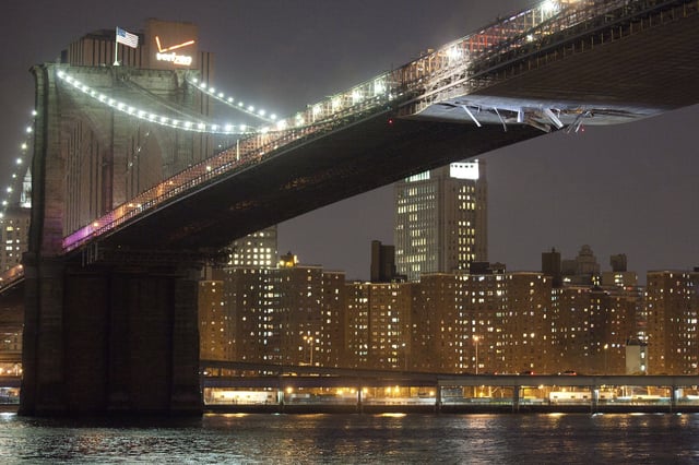 FILE - Sheet metal hangs from the Brooklyn Bridge after a crane being carried on a vessel struck the scaffolding attached to the underside, Monday, March 13, 2012, in New York. (AP Photo/John Minchillo, File)