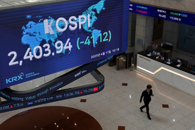 A man passes by a screen showing the Korea Composite Stock Price Index (KOSPI) at the Korea Exchange in Seoul, South Korea, April 11, 2025. REUTERS/Kim Soo-hyeon/File Photo