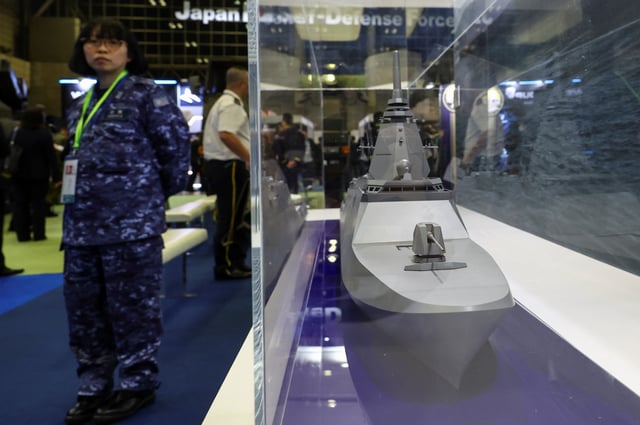 A person stands next to a mock model of the FFM "Upgraded Mogami" class displayed during the Defence Security Equipment International (DSEI) Japan at Makuhari Messe in Chiba, east of Tokyo, Japan May 21, 2025. REUTERS/Kim Kyung-Hoon