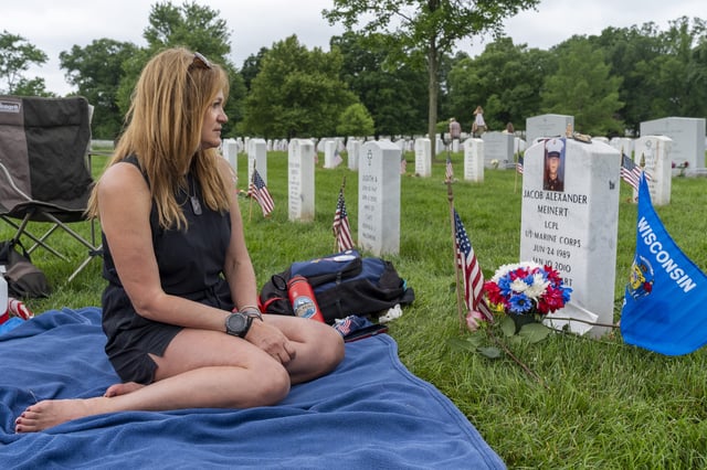FILE - Krista Meinert, of Racine, Wisc., looks at a photo of her son, Marine Lance Corporal Jacob Alexander Meinert, 20, that she attached to his gravestone in Section 60 of Arlington National Cemetery, in Arlington, Va., Monday, May 27, 2024, on Memorial Day. (AP Photo/Jacquelyn Martin, File)