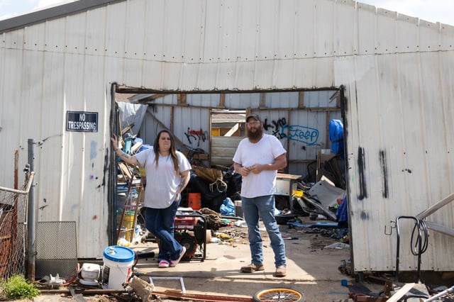 Kymberlie and Robert Watson stand outside a damaged work shed on their property in Cave City, Ark. The March tornado that ripped through the city incurred $60,000 in damages to their home.