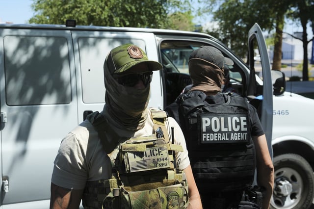 ICE and HSI police protect a van after taking into custody a person outside an immigration court Wednesday, May 21, 2025, in Phoenix.
