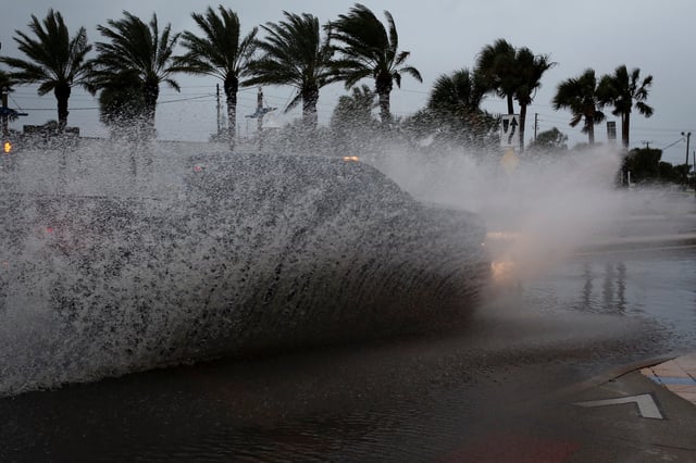 A car drives by a flooded street ahead of the expected arrival of Hurricane Nicole, in Daytona Beach, Florida, U.S., November 9, 2022. REUTERS/Marco Bello/File Photo