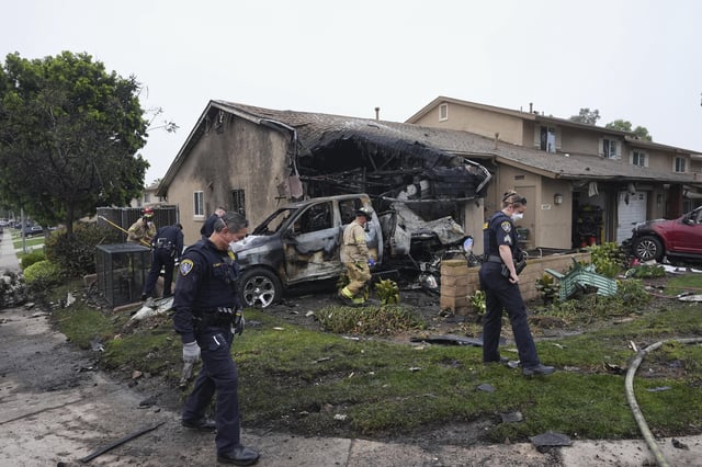 Authorities work the scene where a small plane crashed into a San Diego neighborhood, setting several homes on fire and forcing evacuations along several blocks early Thursday, May 22, 2025. (AP Photo/Gregory Bull)