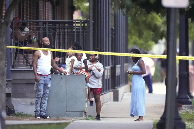 Residents watch as police pursue a fugitive that escaped from a New Orleans jail, Tuesday, May 20, 2025, in New Orleans. (AP Photo/Gerald Herbert)
