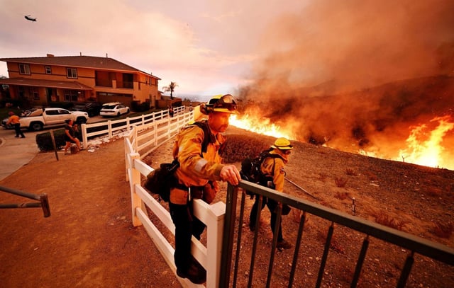 A firefighter climbs over a fence as he battles the Line fire on Emmerton Lane in Highland on Saturday, Sep. 7, 2024. (Photo by Will Lester, Inland Valley Daily Bulletin/SCNG)