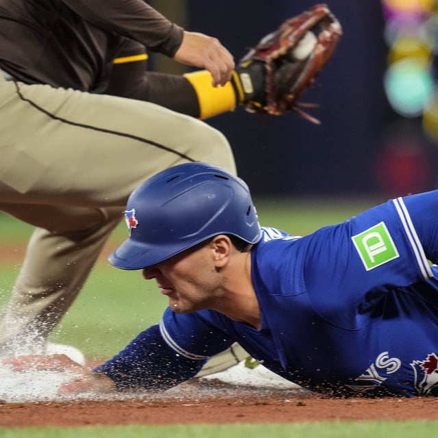 Toronto Blue Jays' Daulton Varsho (5) safely dives back into third base during first inning MLB baseball action against the San Diego Padres in Toronto on Thursday, May 22, 2025. THE CANADIAN PRESS/Chris Young