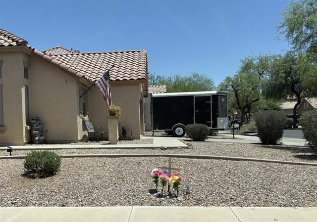 A floral arrangement, a prayer candle and a wooden cross are seen May 22, 2025 in front of a house in Gilbert near Higley and Germann roads. According to police, the home was the site of a shooting that killed Manuel Vega Lopez after the resident, Wyatt Bruce Ford, mistook the landscaper for someone who vandalized and stole from his trailer.