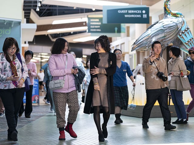  Weihong Liu (centre) walk through the Tsawwassen Mills Shopping Mall in Delta, B.C., May, 18, 2025. Liu has bid to acquire Hudson’s Bay stores in Canada.