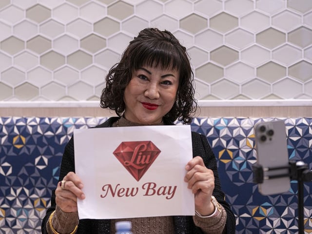 Weihong Liu holds up a sign during her interview with Postmedia at the Tsawassen Mills Shopping Mall in Delta, BC, May, 18, 2025. Liu has bid to acquire Hudson's Bay stores in Canada.