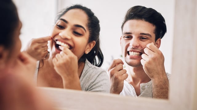 Cropped shot of a young couple flossing their teeth together