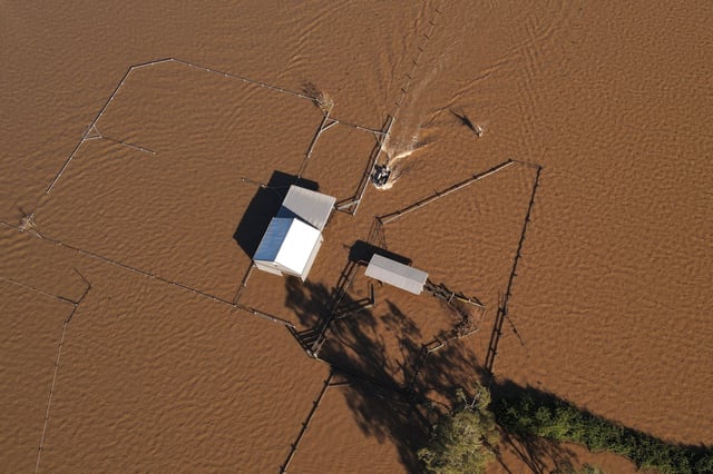 A drone view shows a boat approaching a flooded shed at a stud farm near the Hunter River in Heatherbrae, Australia, May 24, 2025. REUTERS/Hollie Adams