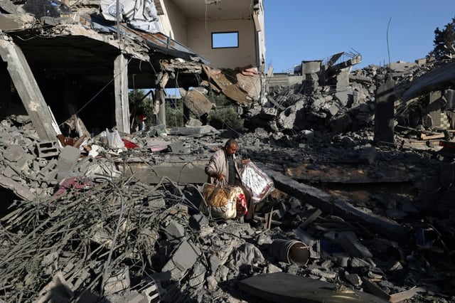 Un Palestinien récupère quelques biens  dans une maison ciblée par une frappe israélienne dans le camp de réfugiés de Nousseirat, dans le centre de la bande de Gaza, le 24 mai 2025