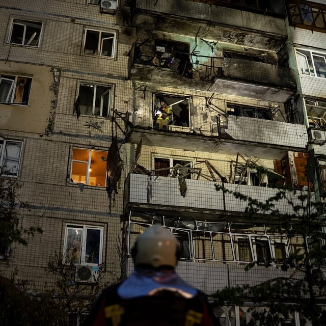 Emergency workers navigates his colleagues at the site of residential building damaged after a Russian attack in Kyiv, Ukraine, Saturday, May 24, 2025. (AP Photo/Alex Babenko)