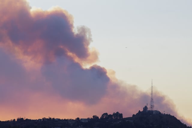 Smoke from the recent Los Angeles wildfires drifts up over the Santa Monica Mountains in Los Angeles, Calif., on Friday, Jan. 10, 2025. The fire has been confirmed to have burned 20,000 acres, killed two people, and destroyed 5,300 homes making it the third most destructive fire in California history. (Photo by Caylo Seals/Sipa USA)(Sipa via AP Images)