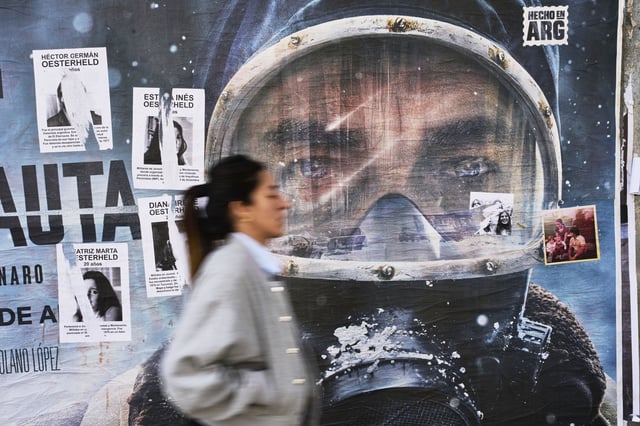 An advertisement for Netflix series "The Eternaut" is partially covered by posters of sci-fi comic author Hector Oesterheld and his daughters, who were forcibly disappeared during Argentina's military dictatorship (1976–1983), in Buenos Aires, Argentina, Tuesday, May 6, 2025. (AP Photo/Rodrigo Abd)