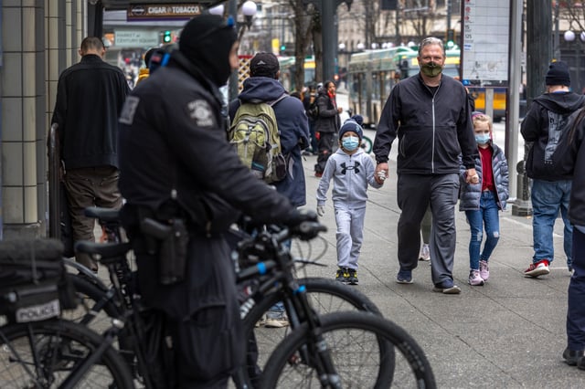 A family walks past Seattle police on 3rd Avenue on March 11, 2022 in downtown Seattle, Washington
