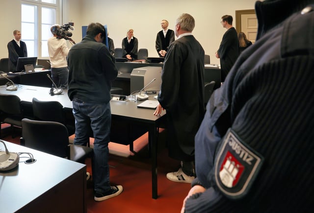 Ein wegen Mordes und besonders schwerer Brandstiftung angeklagter 34-Jähriger (vorne links) und sein Anwalt Fabian Hellweg warten im Gerichtssaal auf den Prozessbeginn.