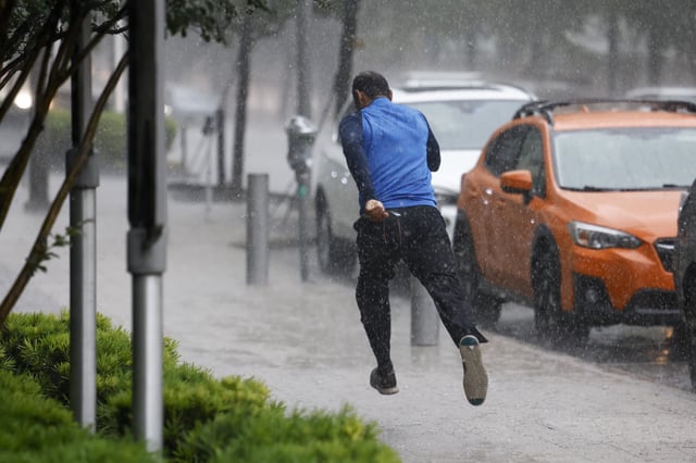 A man runs down the sidewalk along Commerce Street while heavy rain fall in downtown Dallas, Wednesday, April 30, 2025, and a flash flood warning was issued for parts of North Texas through this afternoon. (Elías Valverde II/The Dallas Morning News via AP)