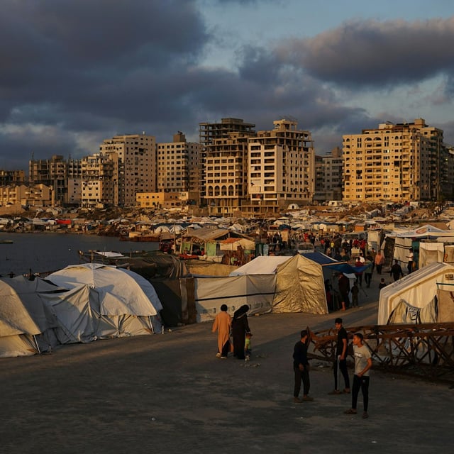 Palästinensische Gebiete, Gaza-Stadt: Vertriebene Palästinenser gehen an einem behelfsmäßigen Zeltlager an der Küste entlang. 
