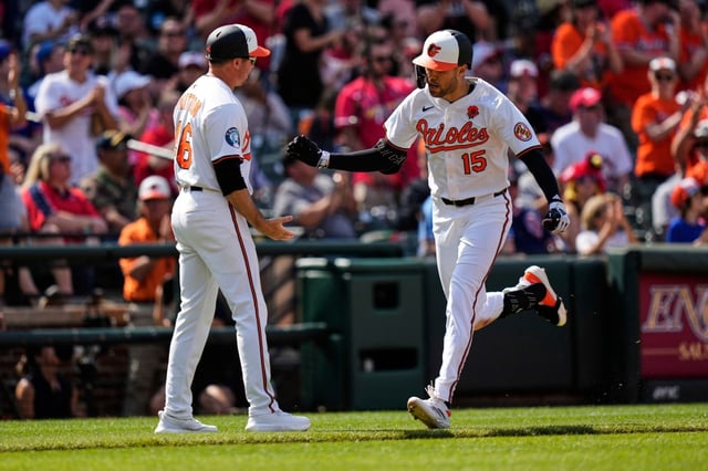 Baltimore Orioles’ Dylan Carlson (15) celebrates with interim third base/infield coach Buck Britton, left, after hitting a three-run home run during the fourth inning of a baseball game against the St. Louis Cardinals, Monday, May 26, 2025, in Baltimore. (AP Photo/Stephanie Scarbrough)