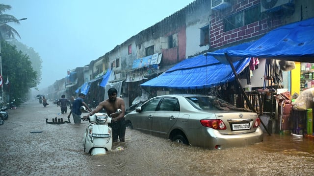 Commuters wade through a severely waterlogged road at Malabar Hill area following heavy rainfall, in Mumbai on Monday. 