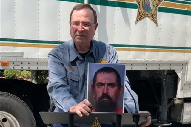 Polk County Sheriff Grady Judd holds up a picture of Timothy Schulz, who was fatally shot by deputies after he had apparently been bitten by an alligator in a Florida lake.