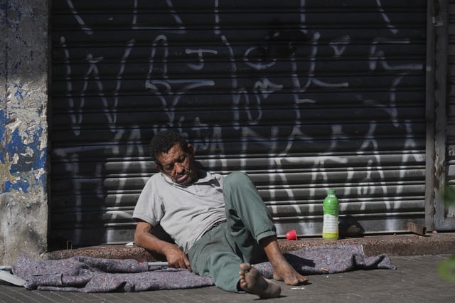 A homeless man sleeps on the sidewalk in a downtown area popularly known as "Crackland" in Sao Paulo, Tuesday, May 20, 2025. (AP Photo/Andre Penner)