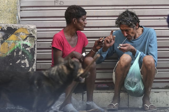 A drug addict smokes crack cocaine in a downtown area popularly known as "Crackland" in Sao Paulo, Tuesday, May 20, 2025. (AP Photo/Andre Penner)
