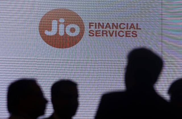 People stand next to a logo of Jio Financial Services ahead of its listing ceremony at the Bombay Stock Exchange in Mumbai, India, August 21, 2023. REUTERS/Francis Mascarenhas/ File Photo