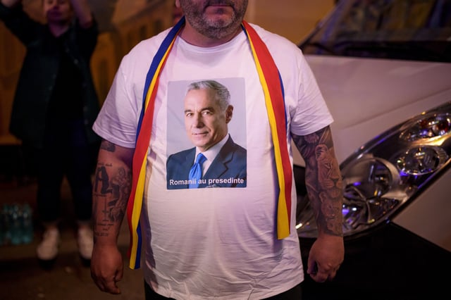 A man wears a t-shirt showing Calin Georgescu, winner of the first round of last year's voided election outside the headquarters of presidential candidate George Simion, after polls closed during the first round of the country's presidential election redo in Bucharest, Romania, Sunday, May 4, 2025. (AP Photo/Andreea Alexandru)