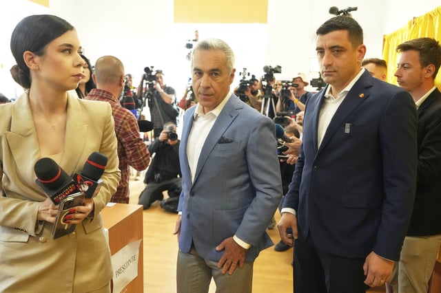 Calin Georgescu, center, winner of the first round of last year's annulled election, leaves with Presidential candidate George Simion after casting their votes in the first round of the presidential election redo in Mogosoaia, Romania, Sunday, May 4, 2025. (AP Photo/Vadim Ghirda)