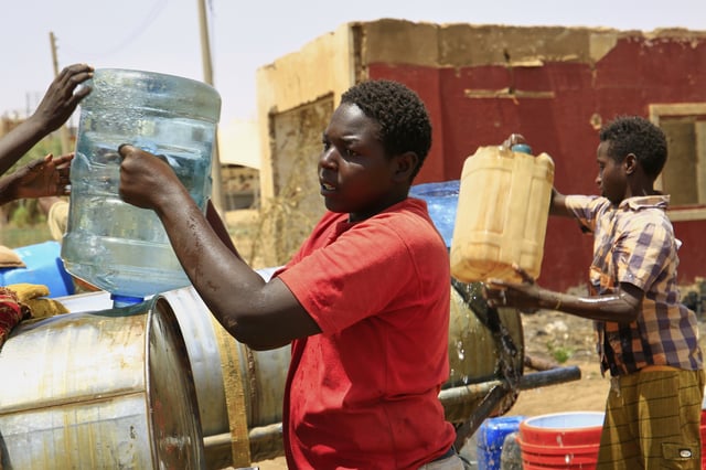 People fill a container by water due to water outages in Khartoum, Sudan, Sunday, May 25, 2025. (AP Photo)