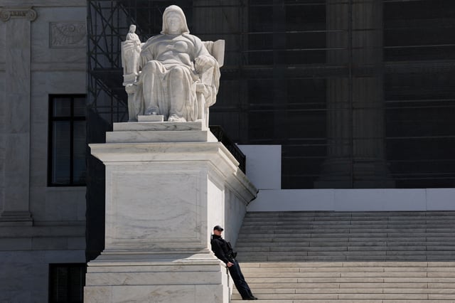 A U.S. Supreme Court Police officer leans against the statue titled the Contemplation of Justice along the front steps of the U.S. Supreme Court building in Washington, D.C., U.S., April 8, 2025. REUTERS/Jonathan Ernst/File Photo