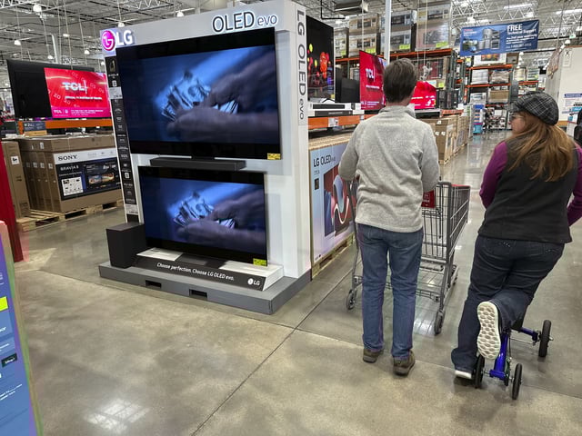 FILE - Shoppers pass by large-screen televisions on display in a Costco warehouse Thursday, Dec. 19, 2024, in Colorado Springs, Colo. (AP Photo/David Zalubowski, File)