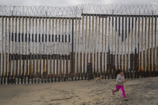 Children playing on the beach near the wall between Mexico and the United States.