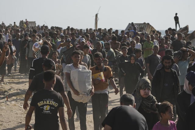 Palestinos cargan con cajas con ayuda humanitaria y comida distribuidas por la fundación de EEUU en Rafah, este martes.