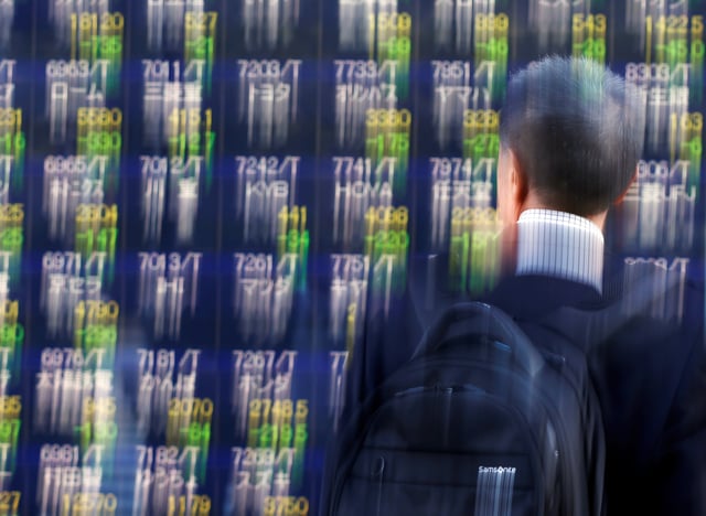 A man looks at an electronic stock quotation board outside a brokerage in Tokyo, Japan, November 9, 2016. Picture taken with slow shutter speed. REUTERS/Issei Kato/File Photo