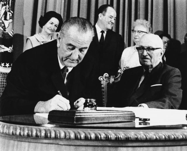 Great Society, Meet Cruelty: President Lyndon Johnson signs the Medicare Bill into law while former President Harry S. Truman, whom Johnson praised as "the real daddy of Medicare," observes during a ceremony at the Truman Library in Independence, Mo. On Sunday, House Speaker Mike Johnson said that Medicaid work requirements have a "moral component" to them because people on Medicaid who "refuse" to work are "defrauding the system." (AP Photo)