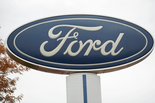 In this Oct. 20, 2019, file photo, the company logo stands over a long row of unsold vehicles at a Ford dealership in Littleton, Colo.