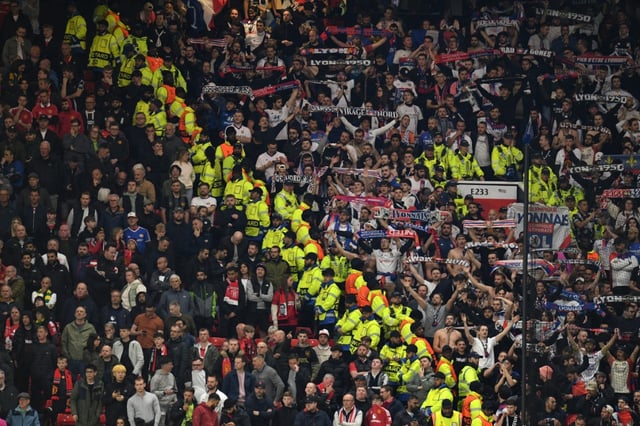 Des agents de sécurité séparent les groupes de supporters rivaux de Manchester United et de Lyon lors du match retour des quarts-de-finale de la Ligue Europa au stade de Old Trafford à Manchester le 17 avril 2025.