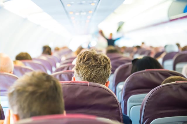 Stock image of flight passengers sitting on a plane.